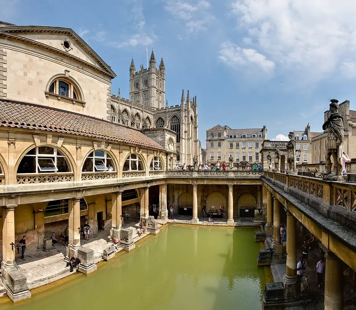 The Great Bath with green spring water, the later surrounding terrace and Bath Abbey beyond