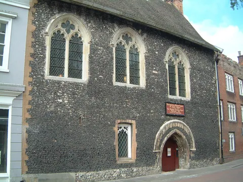 The flint frontage and arched street doorway of Eastbridge Hospital in Canterbury