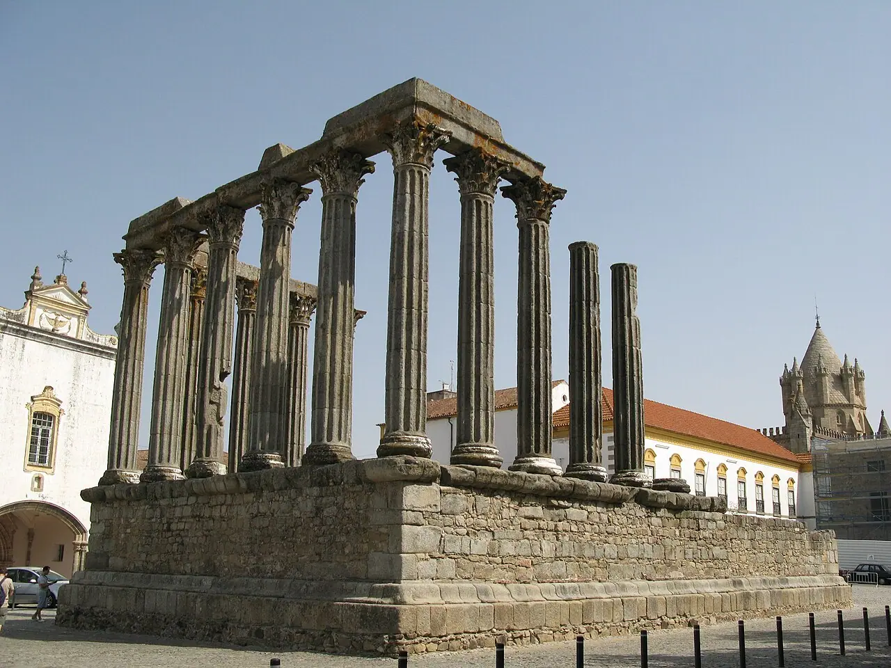 Corinthian columns on the high stone podium of Évora’s Roman Temple, with the cathedral lantern behind.