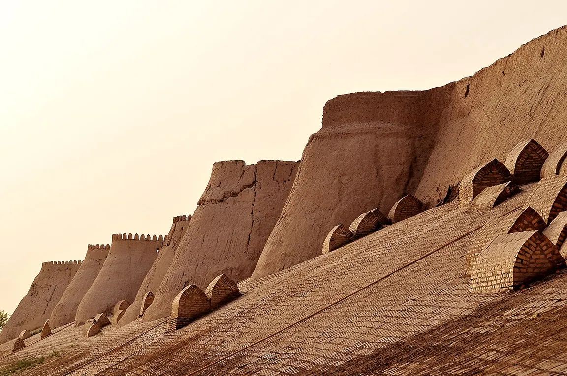 Rounded buttresses along the southern earthen wall of Itchan Kala, with small brick tombs on its slope.