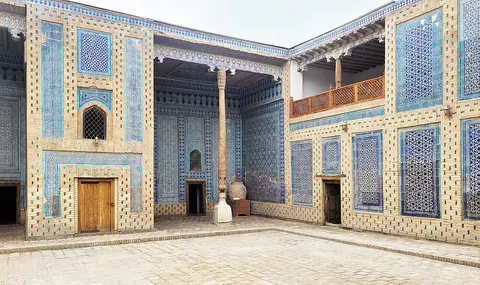 Blue and white tiled walls, carved timber supports and upper balconies around a courtyard of Tash Hauli Palace.