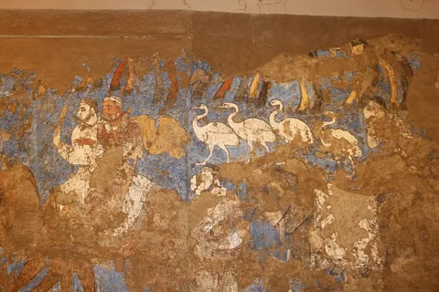A worn seventh-century Afrasiab mural shows pale horses, a camel and figures in a ceremonial procession.