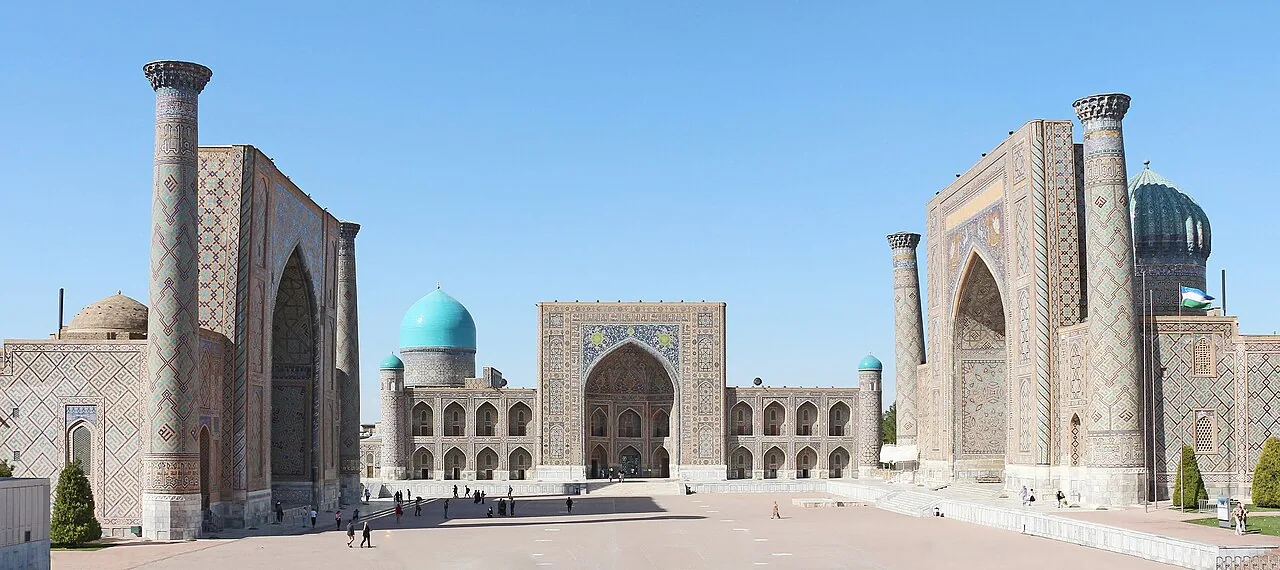 The three tiled madrasahs of the Registan face an open square beneath a clear blue sky.