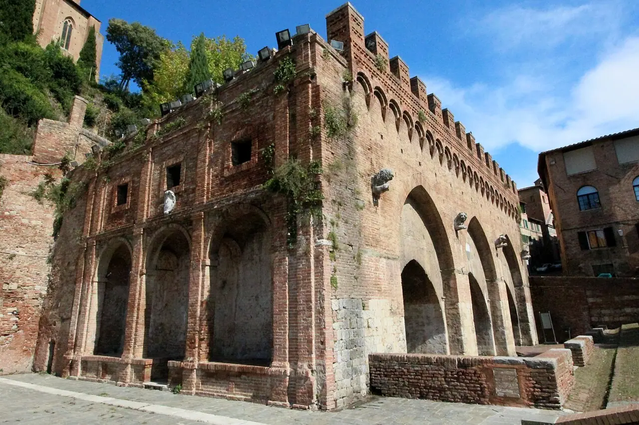 Three pointed arches and crenellated masonry of Fontebranda in Siena