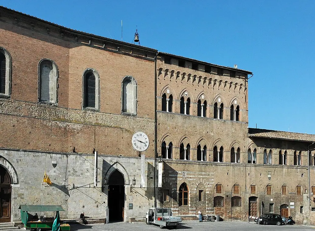 Long brick and stone facade of the former Santa Maria della Scala hospital opposite Siena Cathedral