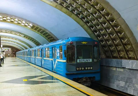 A blue Tashkent metro train at a platform. The guide focuses on Kosmonavtlar station.